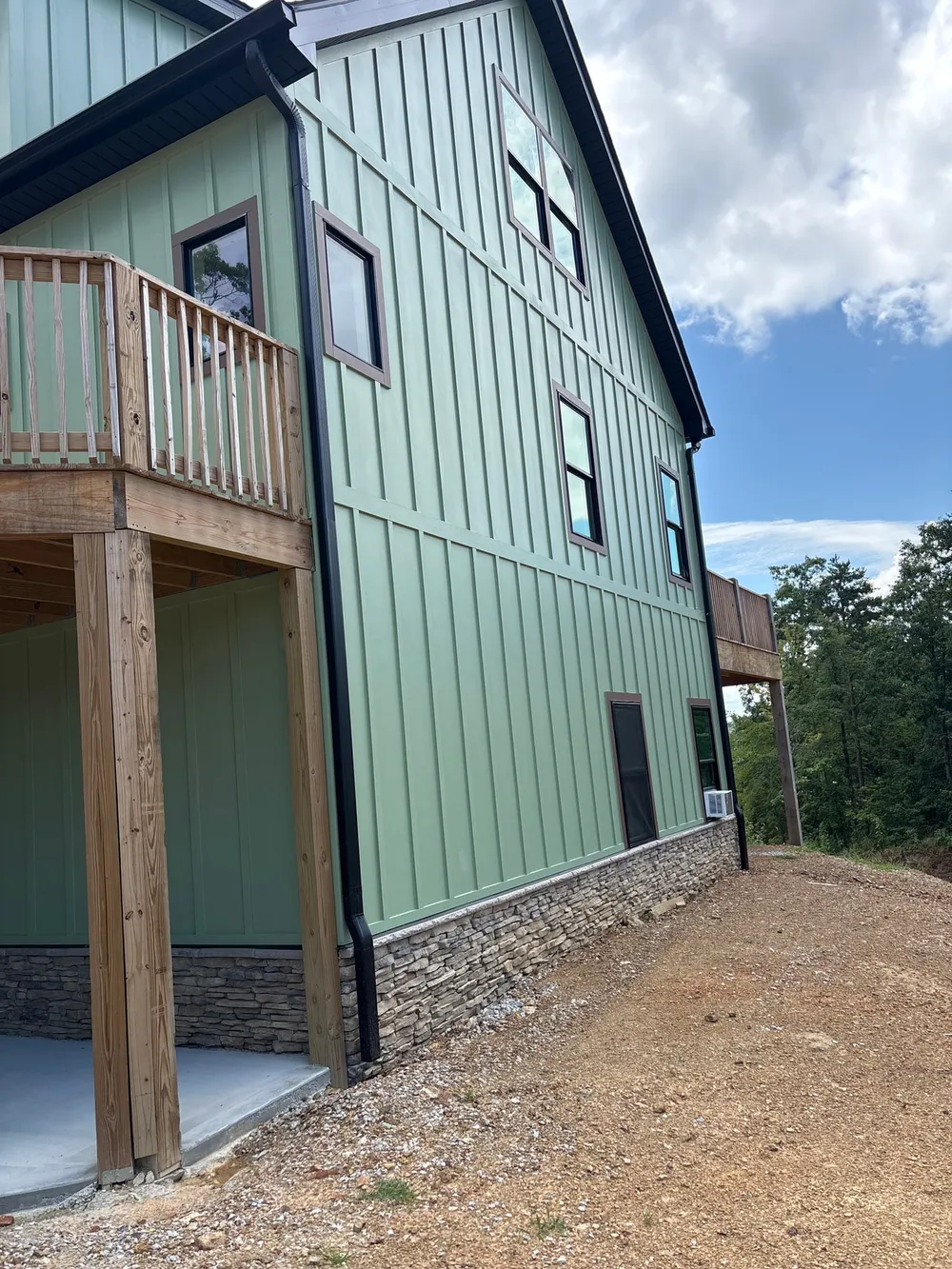 Green board-and-batten exterior with windows, wood trim and stone lower wall