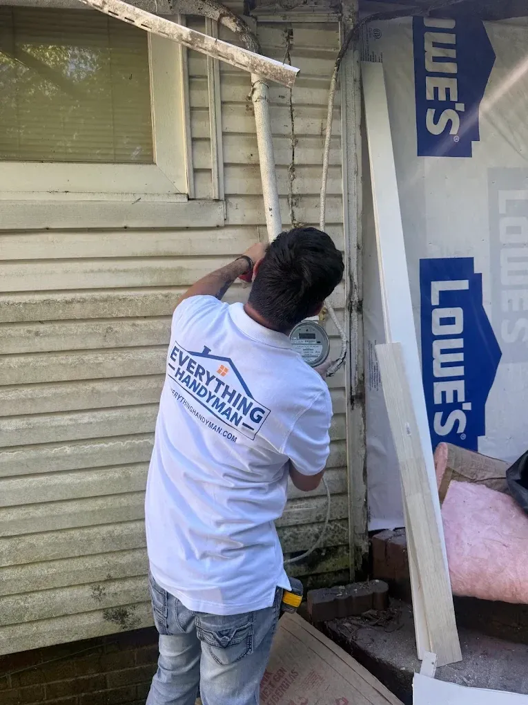 Everything Handyman team member working beside exterior siding and an exposed wall opening