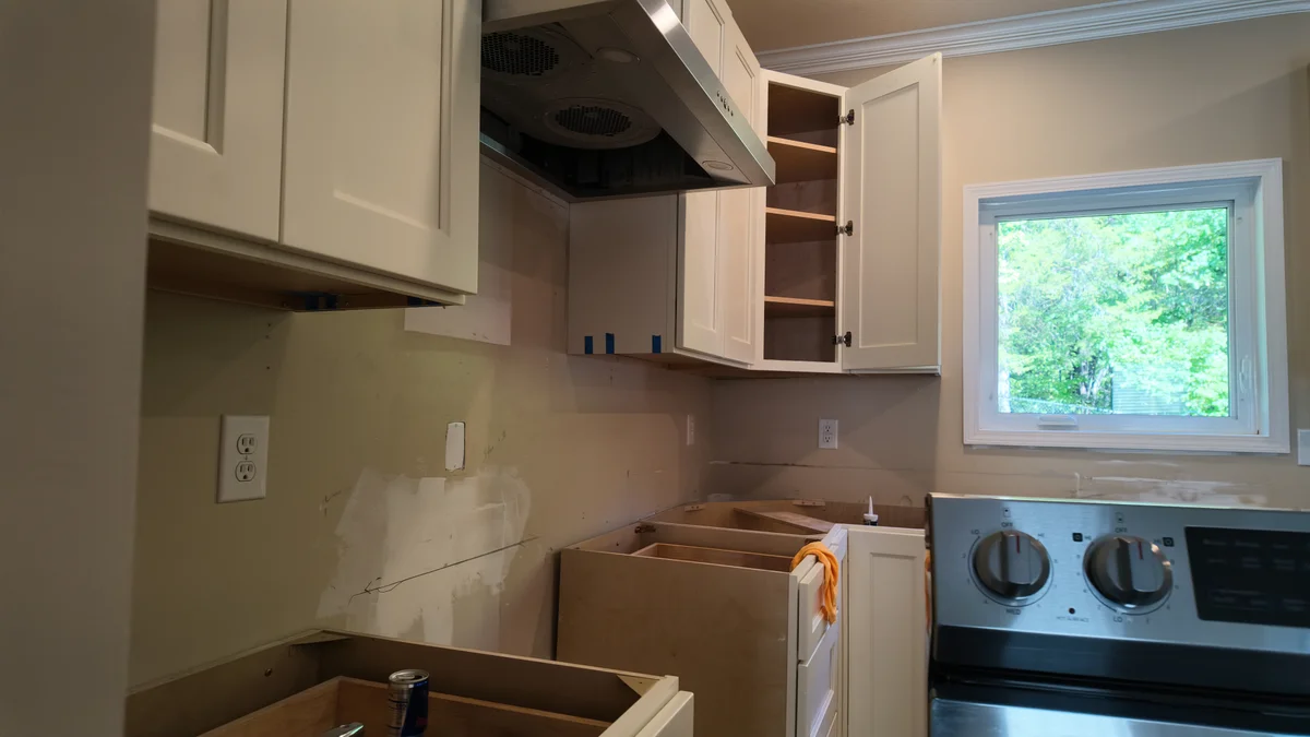 Kitchen cabinet boxes and wall cabinets during installation, with unfinished wall surfaces visible