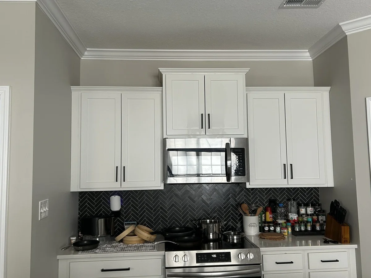 White kitchen cabinets around a range and microwave