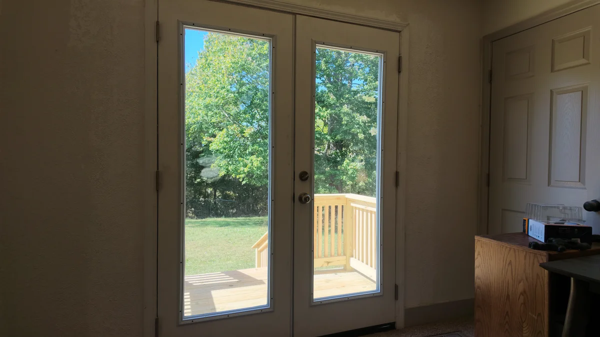 Double glass patio doors viewed from inside a room, with timber steps beyond