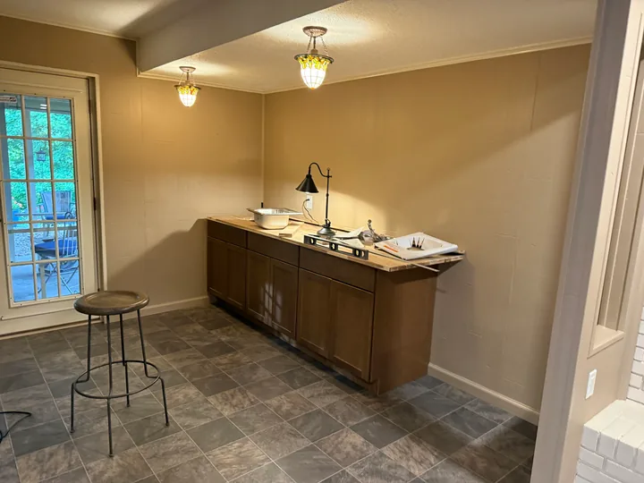 Basement sink cabinet and tiled floor beside an exterior glass door
