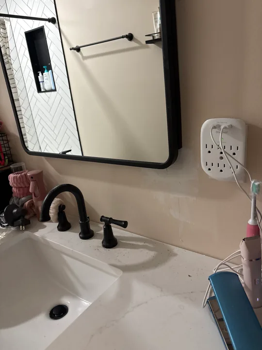White bathroom basin, dark faucet and framed mirror