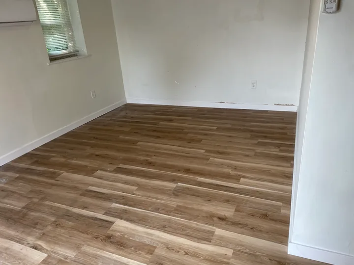 Wood-look plank flooring beside a toilet and white bathroom vanity