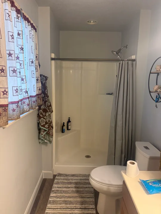 Bathroom with green upper walls, tub surround, vanity and patterned plank flooring