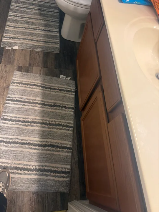 Bathroom with green upper walls, tub surround, vanity and patterned plank flooring