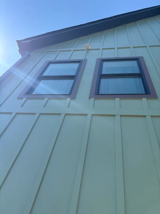 Green board-and-batten siding, windows and exterior wood trim