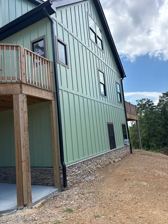 Green board-and-batten siding, windows and exterior wood trim