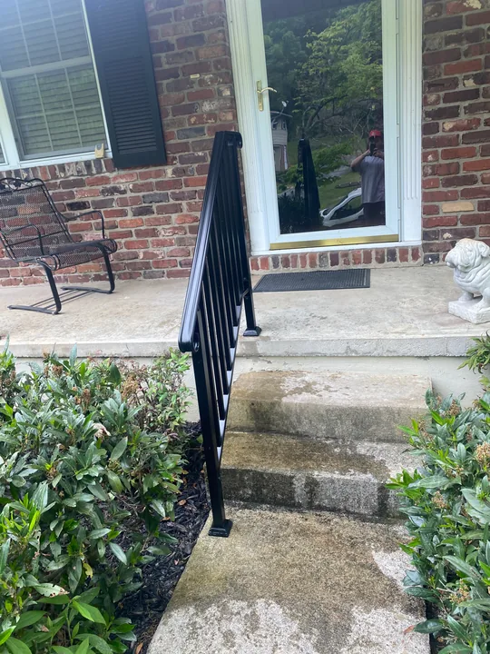 Exterior doorway above masonry steps with a dark metal handrail