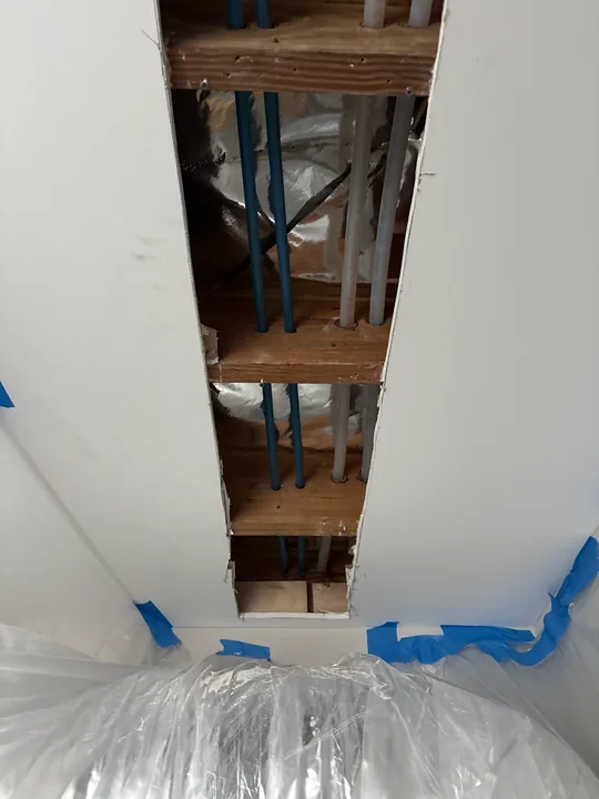 Open strip of ceiling with exposed framing and protected room surfaces