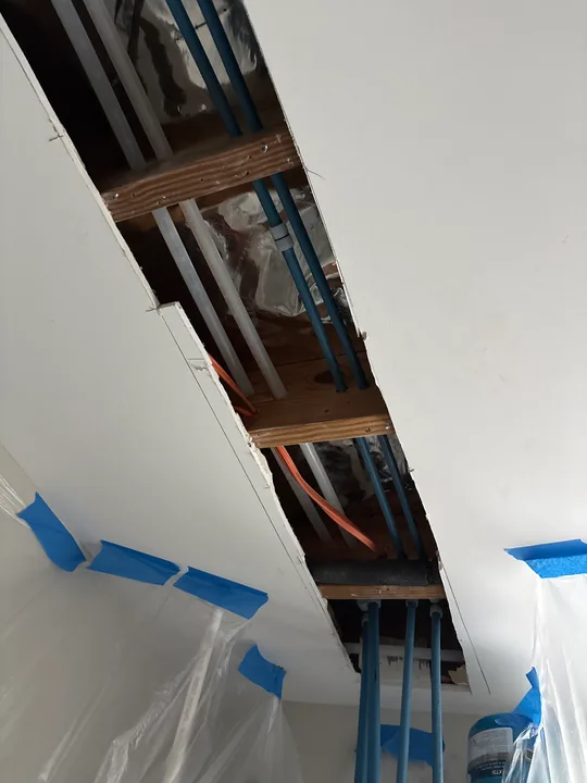 Open strip of ceiling with exposed framing and protected room surfaces