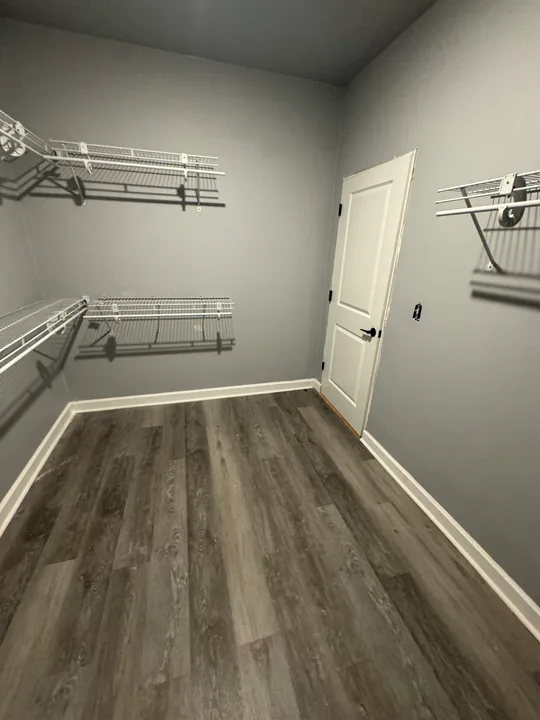 Plank flooring in a closet with white storage rails and shelving