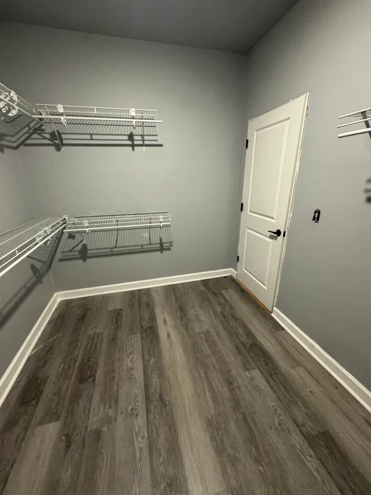 Plank flooring in a closet with white storage rails and shelving