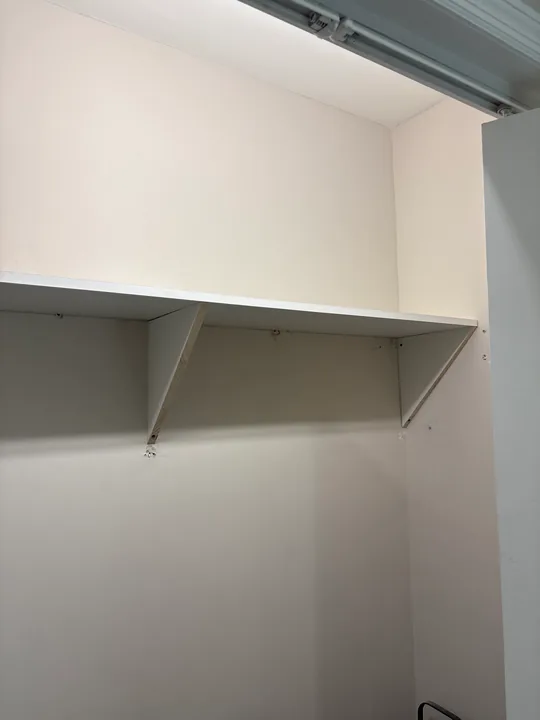 White closet shelves with wall brackets and hanging space