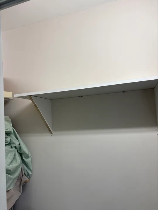 White closet shelves with wall brackets and hanging space