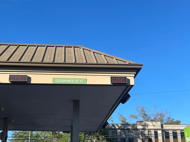 Commercial canopy, metal roof edge and fascia beneath a clear blue sky