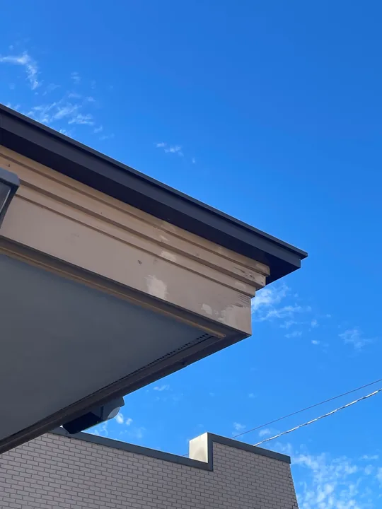Commercial canopy, metal roof edge and fascia beneath a clear blue sky