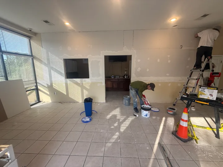 Crew working on partition seams and ceiling finishes in a commercial interior