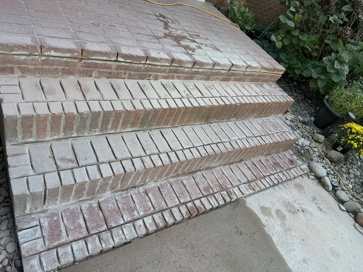 Exterior concrete and masonry steps beside a brick entrance