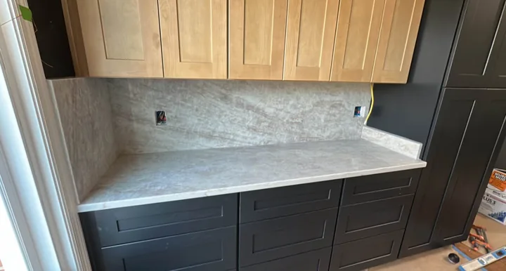 Dark kitchen cabinets, light counter and stone-look backsplash