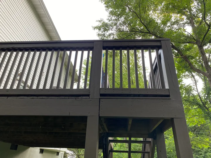 Dark deck railing and perimeter trim beside a home