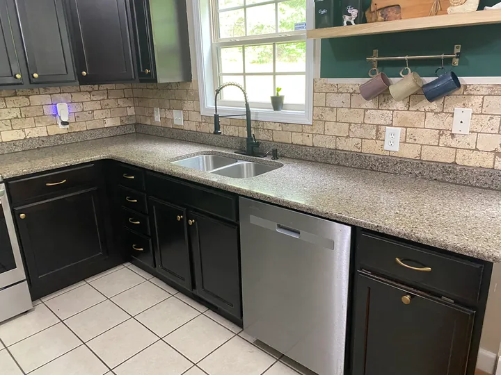 Dark kitchen cabinetry, tiled backsplash and light countertops