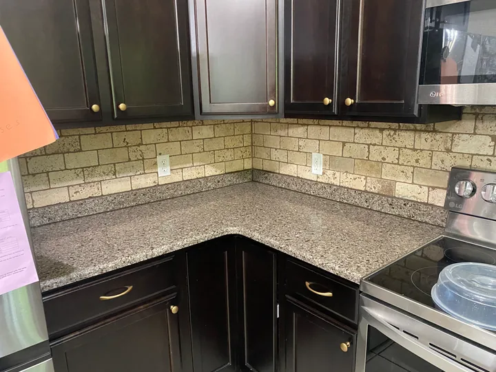 Dark kitchen cabinetry, tiled backsplash and light countertops
