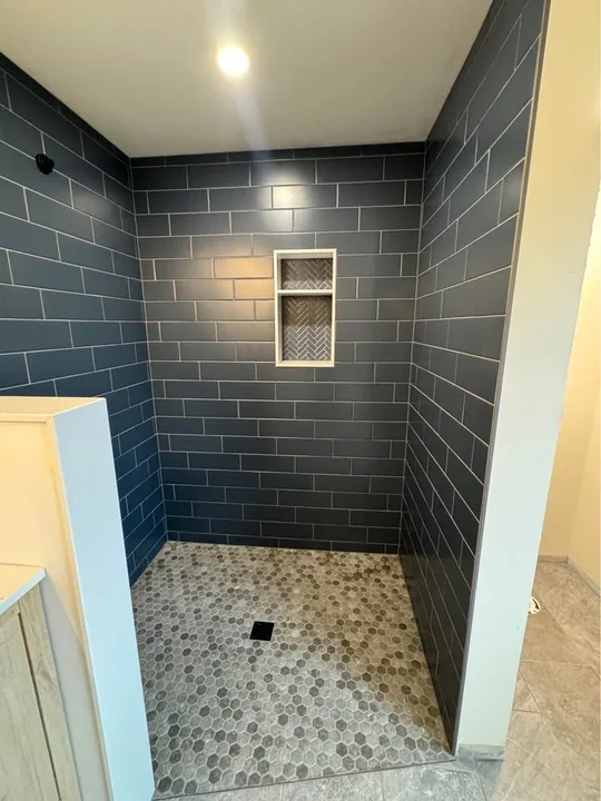 Shower with dark rectangular wall tile, recessed niche and mosaic floor