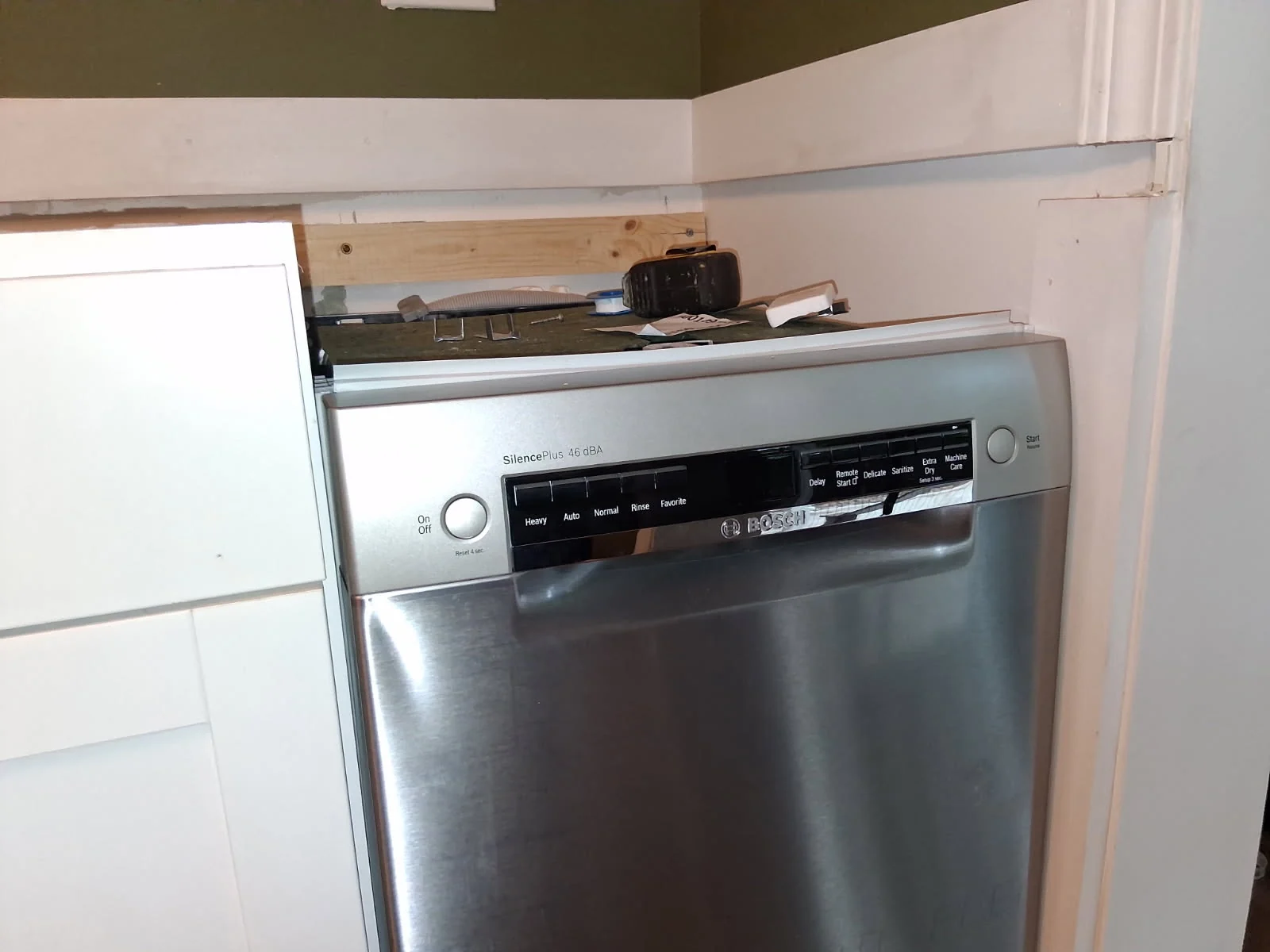 Dishwasher beneath a kitchen counter beside light cabinets