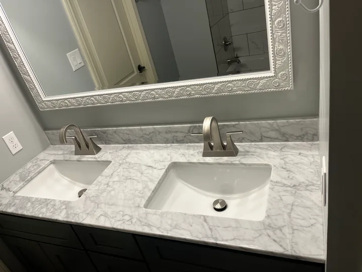 Dark double vanity, white basins and a broad framed bathroom mirror