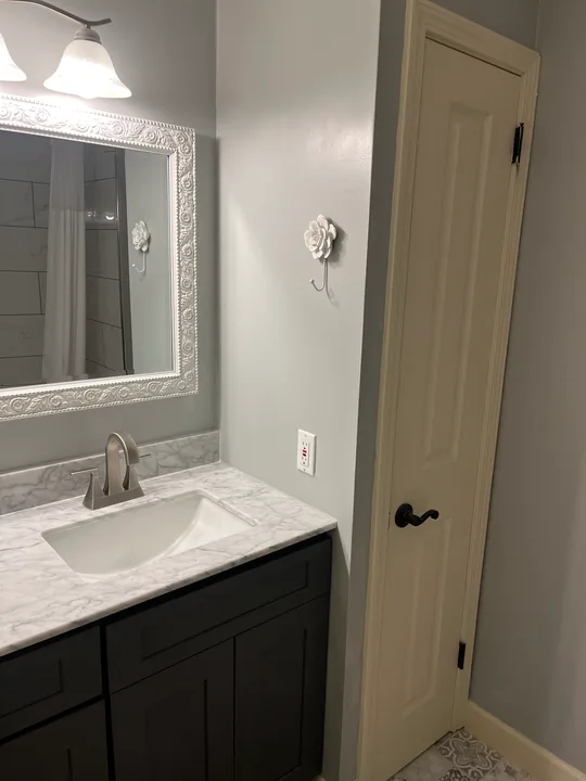 Dark double vanity, white basins and a broad framed bathroom mirror