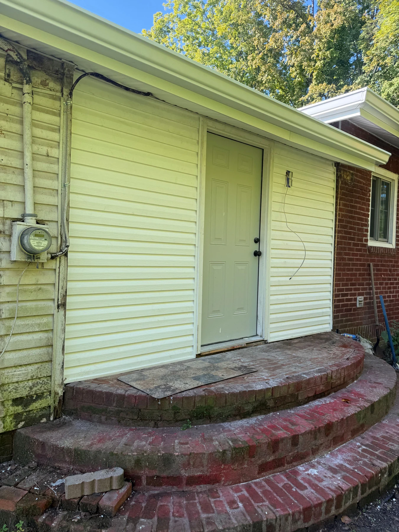Updated siding, paneled exterior door and roof-edge trim above the curved brick steps