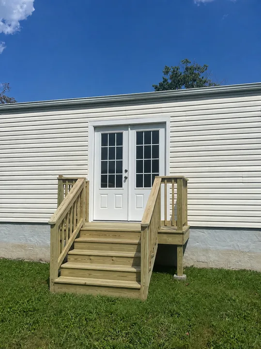 Timber entry steps and double exterior doors beside a home