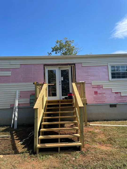 Timber entry steps and double exterior doors beside a home