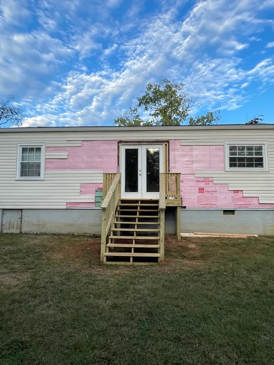 Timber entry steps and double exterior doors beside a home
