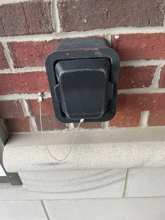 Supra key lockbox with protective cover mounted on brick