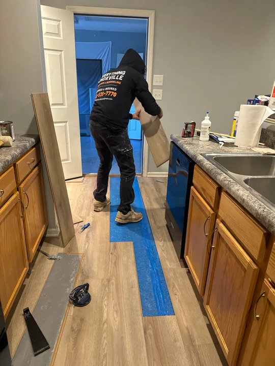 Gray plank flooring and installation work beside a bathroom vanity