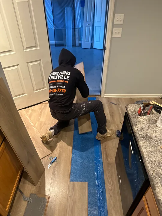 Gray plank flooring and installation work beside a bathroom vanity