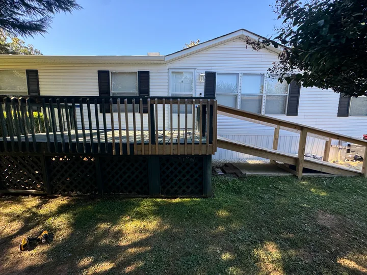 Gray deck, dark railings and a long access ramp beside a home