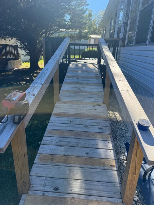 Gray deck, dark railings and a long access ramp beside a home