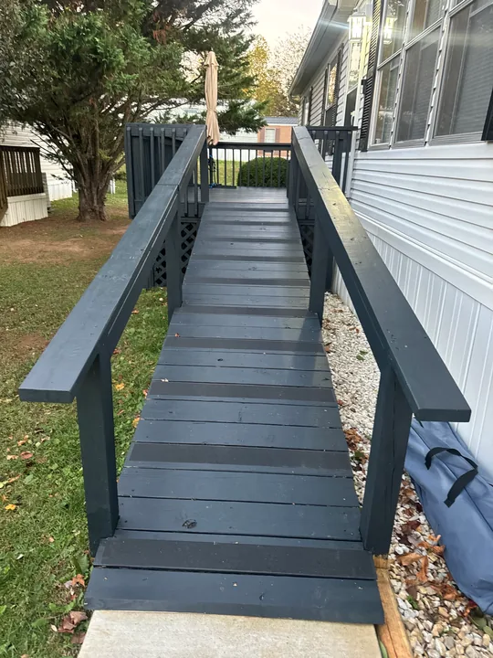 Gray deck, dark railings and a long access ramp beside a home