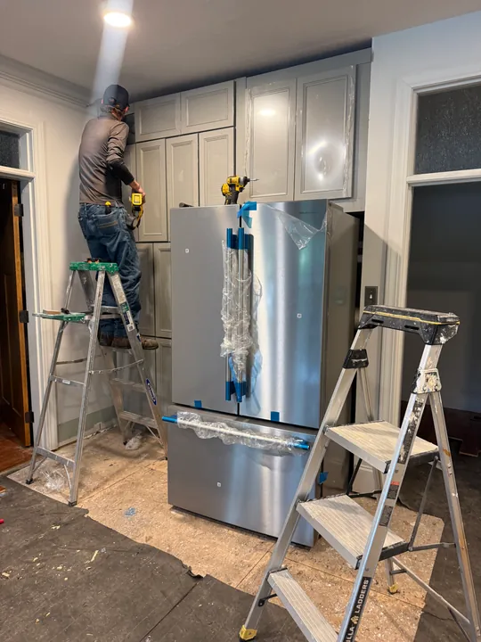 Crew working above the wrapped refrigerator during our full kitchen remodel