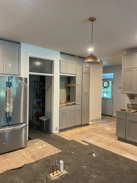 Gray kitchen cabinetry, appliance opening and refrigerator beside the pantry doorway