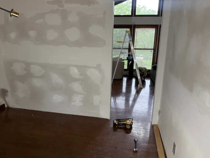 Prepared drywall joints beside a tall window and interior opening