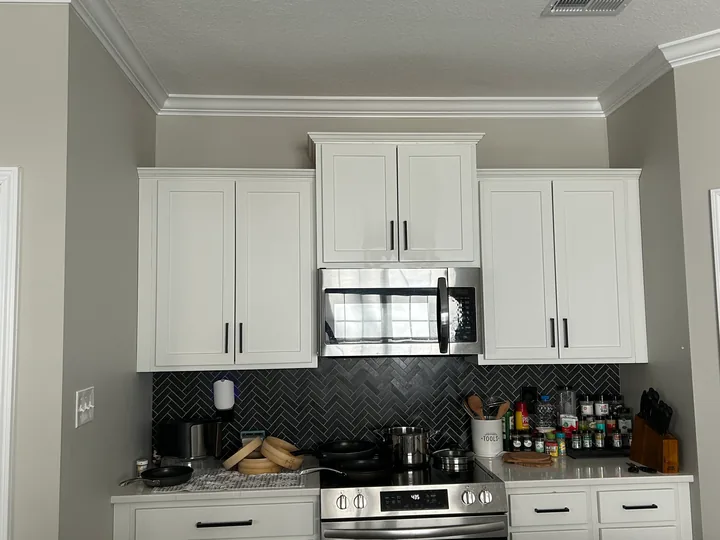 White kitchen cabinets, dark hardware and tiled backsplash