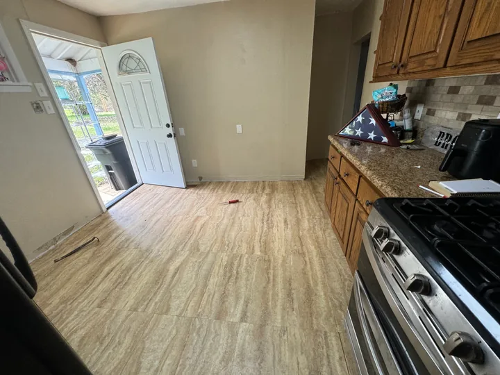Plank flooring beside kitchen cabinetry and door thresholds