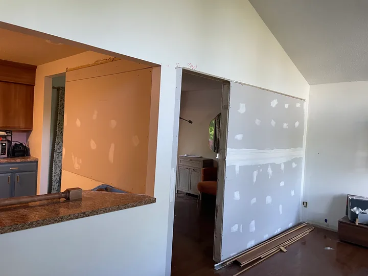 Kitchen wall with drywall patches and joint compound beside cabinets
