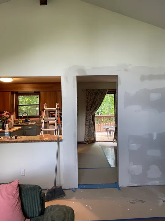 Kitchen wall with drywall patches and joint compound beside cabinets