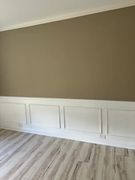Light plank flooring beside white wall paneling and baseboards