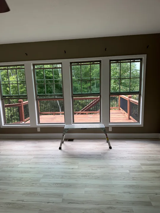 Light plank flooring beside white wall paneling and baseboards